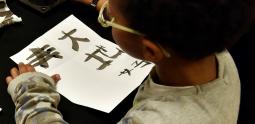 Atelier jeune public, enfant entrain d'écrire à l'encre chinoise 